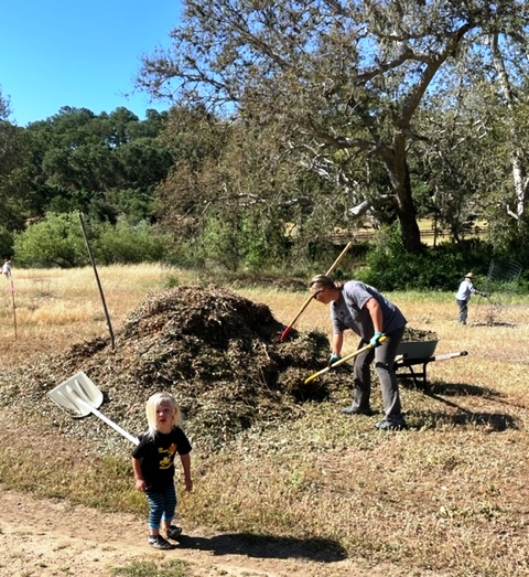 Rhys and Lauren loading a wheelbarrow with mulch!